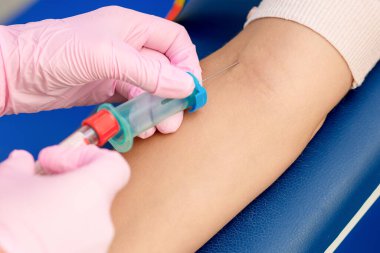 Coronavirus aşısını tanıtan ve kolun damarına iğne batıran hemşire ellerinin yakın çekimi..