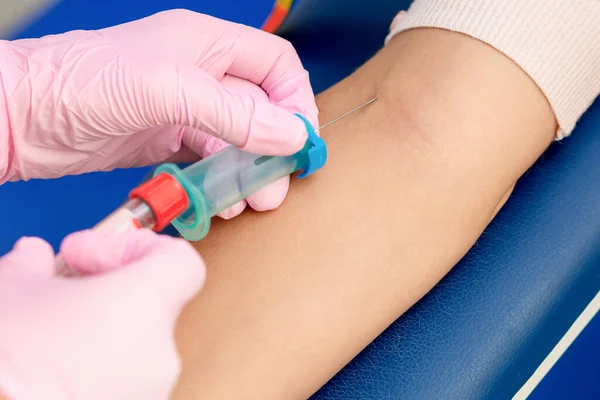 Coronavirus aşısını tanıtan ve kolun damarına iğne batıran hemşire ellerinin yakın çekimi..