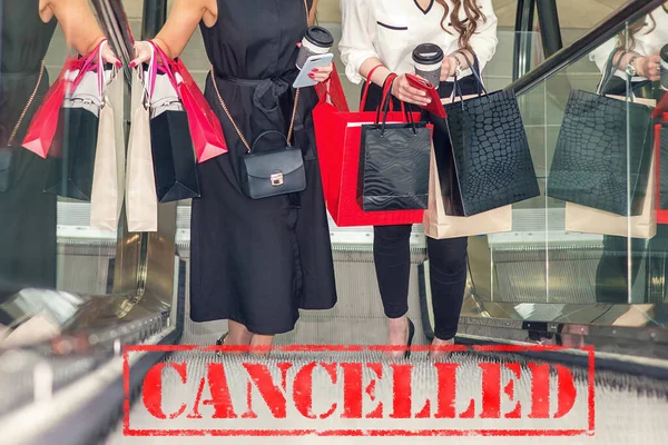 Word CANCELLED on background of two young women in the shopping mall. Coronavirus quarantine. Closed shopping mall.