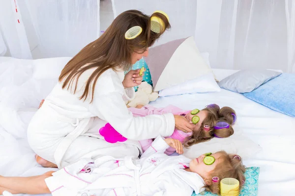 Mother Two Daughters Putting Cucumbers Eyes Curlers Hair Lying Bed — Stock Photo, Image