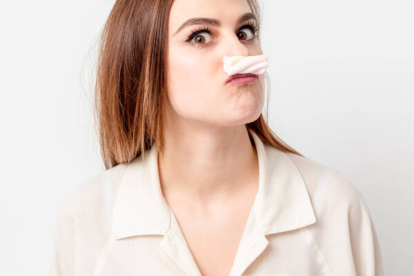 Young woman making mustache with sweet candy marshmallow on white background. Depilation and epilation concept.