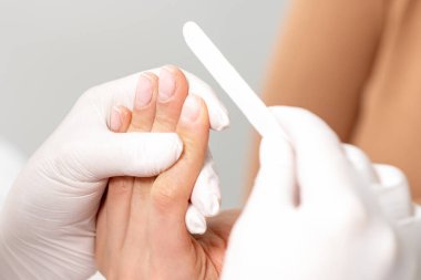 Manikür ustasının elleri, tırnak törpüsüyle kadın tırnaklarını parlatırken..