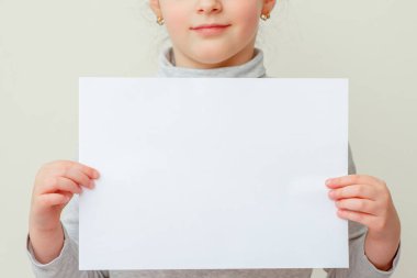 Kızın elindeki boş kâğıt parçalarını taklit et. Çocuk boş sayfayı beyaz arkaplanda ileti için hazır tutuyor.