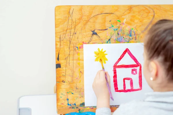 Kind Zeichnet Während Der Schulzeit Gelbe Sonne Mit Rotem Haus — Stockfoto