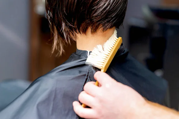 Hand os hairdresser is cleaning neck with brush from cutted hair after haircut.