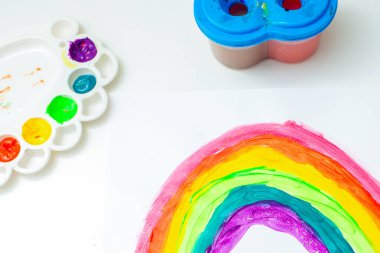 Beyaz bir kağıt üzerinde suluboya bir fırça ile gökkuşağının üst görünümü. Evde kal ve koronavirüs salgını konsepti. Gökkuşağı çizimi.