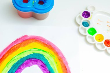 Beyaz bir kağıt üzerinde suluboya bir fırça ile gökkuşağının üst görünümü. Evde kal konsepti.