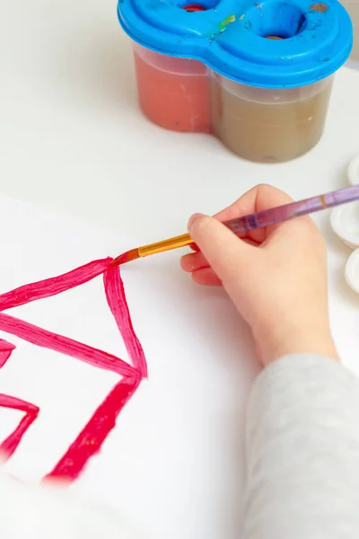 白い紙に水の色で家を描くブラシで子供の手の閉鎖 — ストック写真