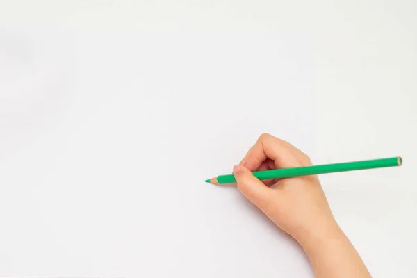 准备用绿色铅笔在白纸背景上画的孩子的手的顶部视图 复制文本的空间 莫科普 — 图库照片