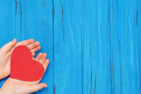 Kırmızı kalp çocukların elinde mavi ahşap zemin üzerinde metin için fotokopi alanı var. Çocuk sevgisi kavramı.