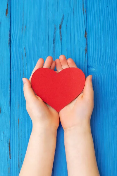 Ręce Dziecka Trzymające Ręcznie Robione Czerwone Serce Niebieskim Drewnianym Tle — Zdjęcie stockowe