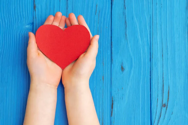 Κόκκινη Καρδιά Στα Χέρια Των Παιδιών Στο Μπλε Ξύλινο Φόντο — Φωτογραφία Αρχείου