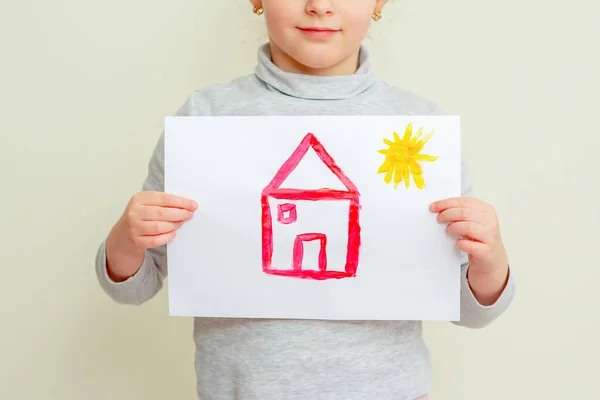 小孩的衣服拿着红房子的照片 她的脸被太阳照在黄色的背景上 小学绘画学校 — 图库照片