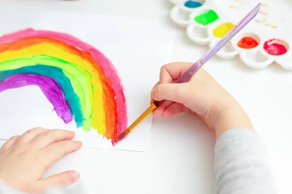 小さな子供の手はブラシで水彩で虹を描きます — ストック写真