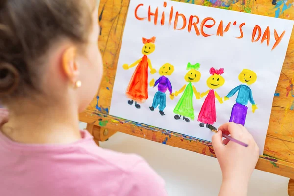 小さな女の子は言葉で子供の日休日のための木製のイーゼルに子供の日を描いています幸せな子供の日 — ストック写真