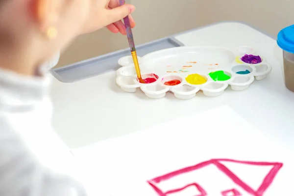 小さな子供の手は赤い家を水彩で描いています 子供の創造性 — ストック写真