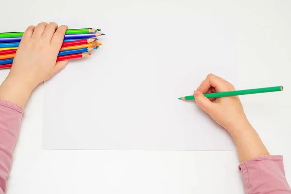 用绿色铅笔在白纸上画图 手里拿着一束彩色铅笔 俯瞰着小孩的手 有选择的重点 — 图库照片