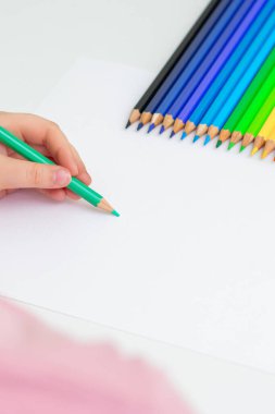 Renkli kalemlerle boş kağıda çizen küçük bir çocuğun dikey görüntüsü. Uzayı metin için kopyala. Modelleme. Seçici odak.