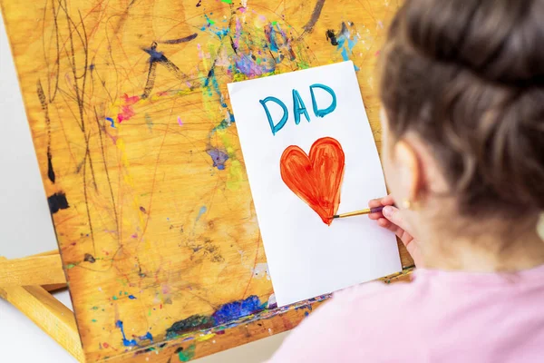子供の手は赤いハートを描き 単語はお父さんはイーゼルの白い紙にグリーティングカードを渡します 幸せな父の日のコンセプト — ストック写真