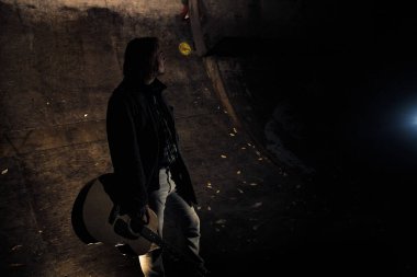 Akşamın geç saatlerinde elinde gitar olan genç bir adam.