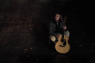 Akşamın geç saatlerinde elinde gitar olan genç bir adam.
