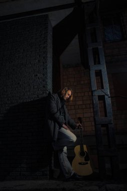 Akşamın geç saatlerinde elinde gitar olan genç bir adam.