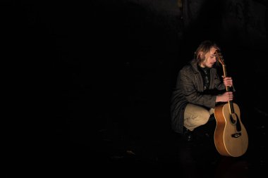 Akşamın geç saatlerinde elinde gitar olan genç bir adam.