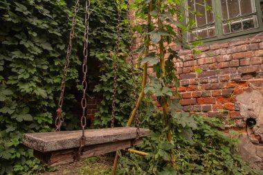 Eski ahşap salıncaklar tuğla duvarlı bir bahçede