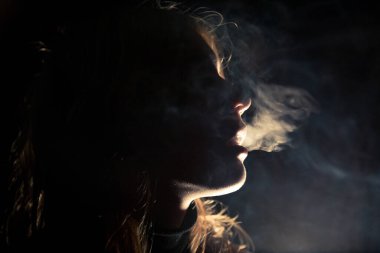 Geceleri şehirde sigara içen bir bayan.