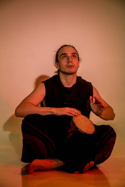 Genç bir adam dumanda bongo çalıyor.