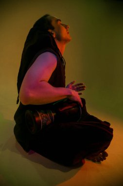 Kapüşonlu bongo çalan genç bir adam.