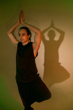 Joga giymiş bir adam yeşil ışıkta poz verir. 