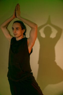 Joga giymiş bir adam yeşil ışıkta poz verir. 