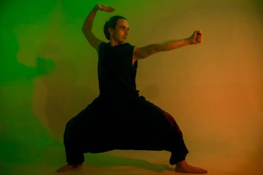 Joga giymiş bir adam yeşil ışıkta poz verir. 