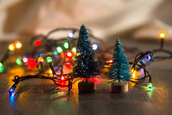 Zwei kleine grüne Weihnachtsbäume als Symbol des neuen Jahres auf hölzernem Hintergrund mit lila Sternen, Lametta, Draufsicht, Platz für Text und Untergrund — Stockfoto
