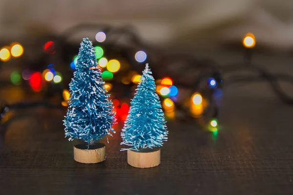 Two little green Christmas trees as a symbol of the new year on wooden background with purple stars, tinsel, top view, there is place for the text and substrate — Stock Photo, Image