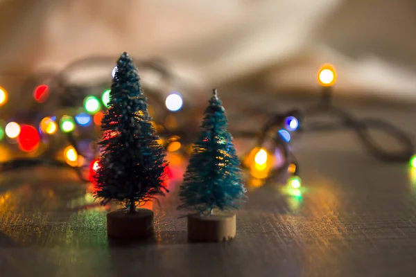 Two little green Christmas trees as a symbol of the new year on wooden background with purple stars, tinsel, top view, there is place for the text and substrate — Stock Photo, Image