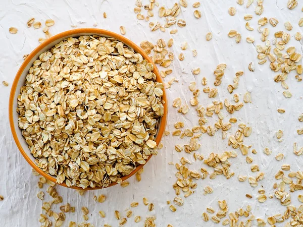 Harina de avena laminada en seco en un tazón sobre fondo blanco. Vista superior. espacio para texto — Foto de Stock