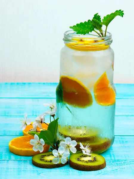 Voda s mandarinkami, mátou a malými kvítky na dřevěné pozadí. Selektivní fokus — Stock fotografie