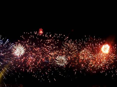 Havai fişekler göz kamaştırıcı bir gösteriyle gökyüzünü aydınlatıyor. Kutlama konsepti. Gökyüzündeki havai fişeklerin işi, karanlık gökyüzündeki renkli havai fişekler, gece