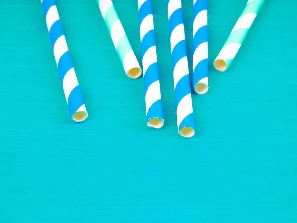 Colorful paper straws on blue wooden background. Event and party supplies.