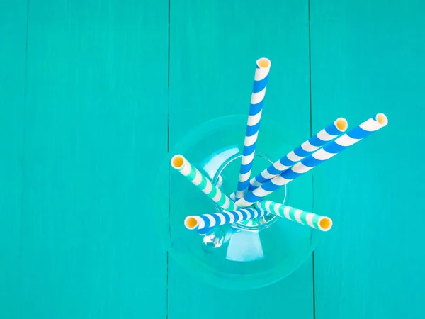 Colorful paper straws on blue wooden background. Event and party supplies.