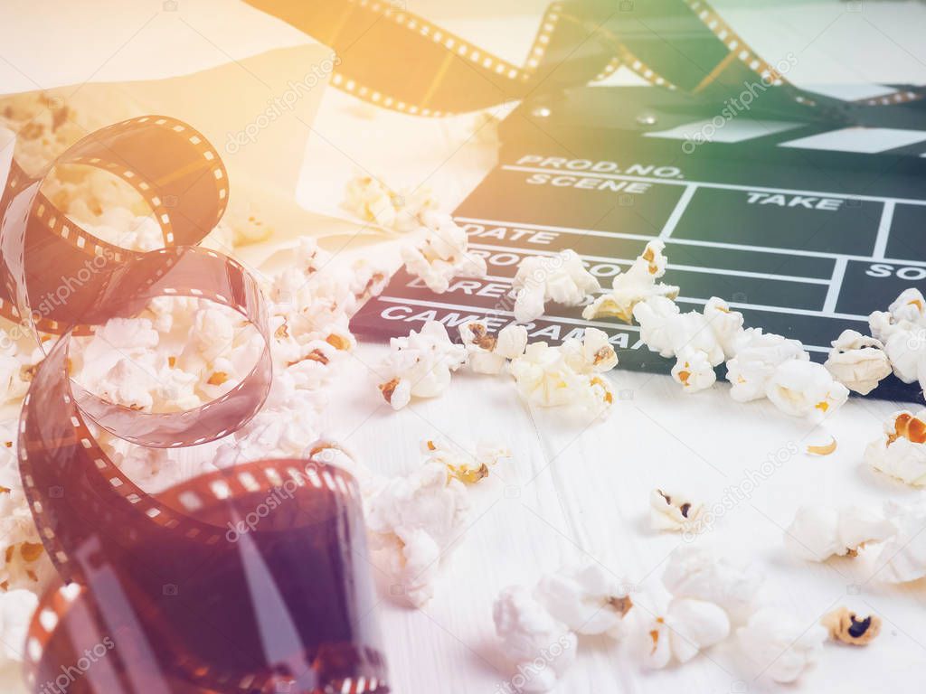 Clapperboard, a roll of film, and popcorn on the table