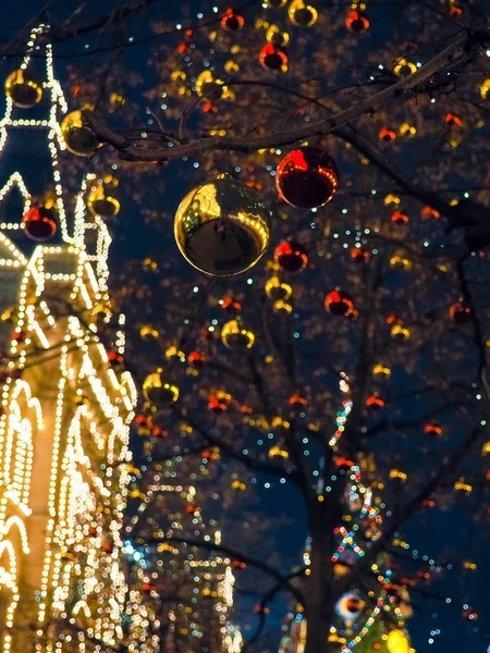 Iluminacja Świąteczna na ulicach miasta, drzewa z jasne czerwone i żółte kulki. — Zdjęcie stockowe