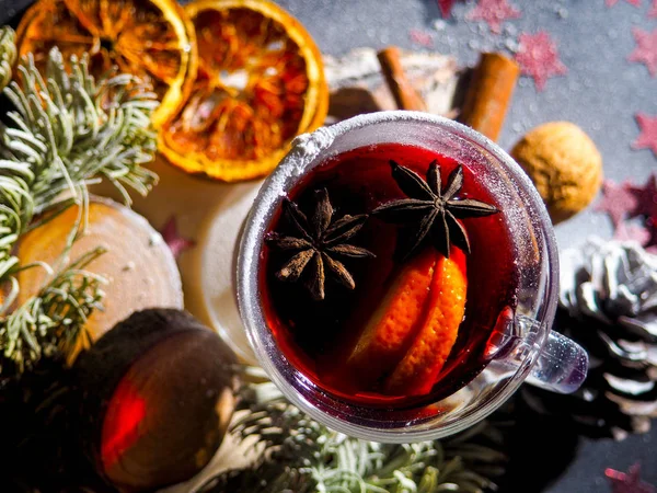 Christmas mulled wine with spices in glasswith plaid and snow on a christmas tree on dark background, The glass cup of hot winter drink — Stock Photo, Image