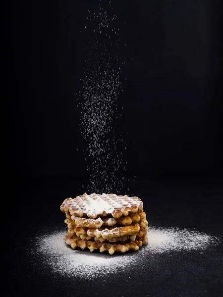 Beyaz plaka ile üstüne pudra şekeri siyah arka plan, çok lezzetli aperatif üzerine döktü eleme ev yapımı Belçika waffle. eski ahşap masa üzerinde şeker. Karanlık rustik tarzı. kopya alanı, şık