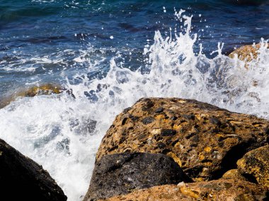 Kayalık sahil, denize karşı çarpan dalgalardan sıçramalarına olan lacivert beyaz sprey ile