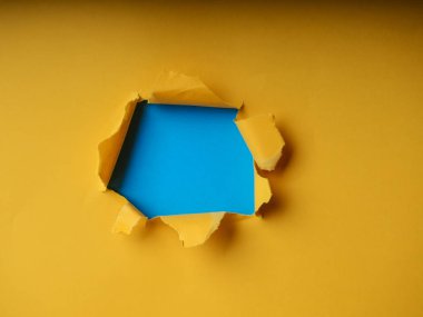 Metin, baskı veya tanıtım içeriğiniz için sarı arka plan üzerinde yırtık kenarları olan küçük kağıt deliği. Kağıt yoluyla. Yırtık delik. Kimse yok. Doğru atış. Reklam cılık ve çığır açan konsept