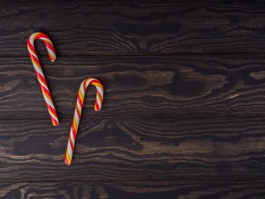 Eski ahşap bir masada şeker kamışı. Noel arkaplanı. Noel, yeni yıl tatili geçmişi. Tebrik kartı düzlüğü ahşap masanın üzerinde, üst manzara