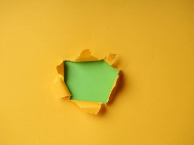 Metin, baskı veya tanıtım içeriğiniz için sarı arka plan üzerinde yırtık kenarları olan küçük kağıt deliği. Kağıt yoluyla. Yırtık delik. Kimse yok. Doğru atış. Reklam cılık ve çığır açan konsept